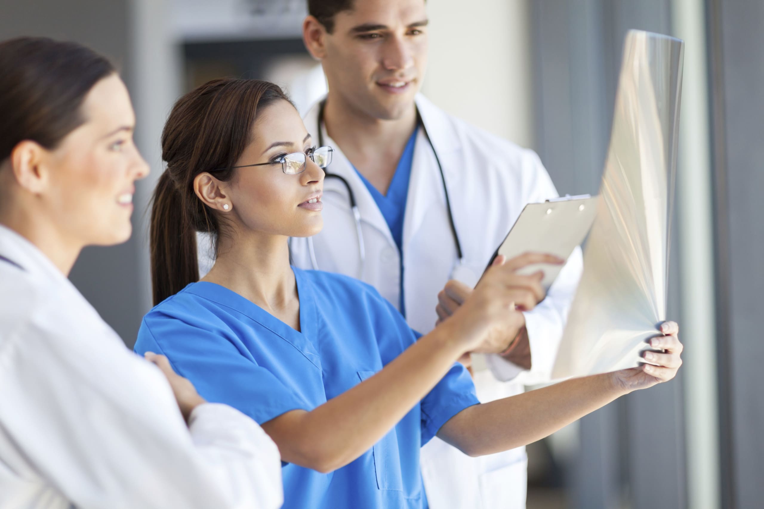Healthcare team reviewing a clipboard together in a bright hospital corridor.