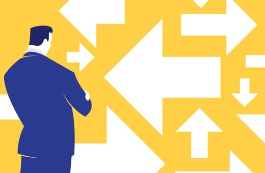 Businessperson in a blue suit stands before a wall of white arrows on a yellow background, symbolizing choices and direction.