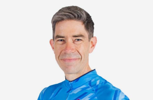 Smiling man in a blue athletic jersey against a white background (portrait).